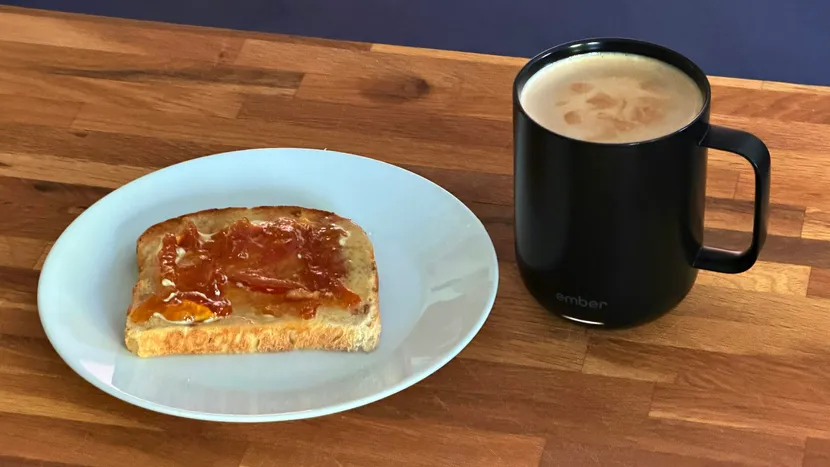 Toast with jam and a mug of coffee on a wooden table.