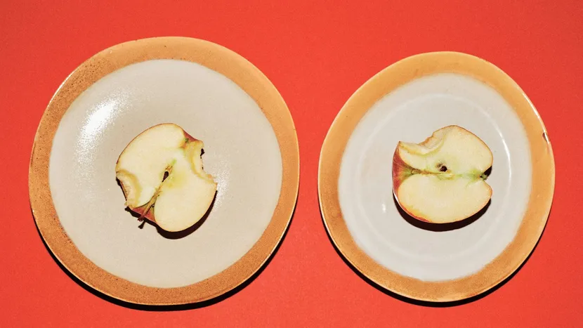 Two halves of the same apple, each on its own plate, against a red background.