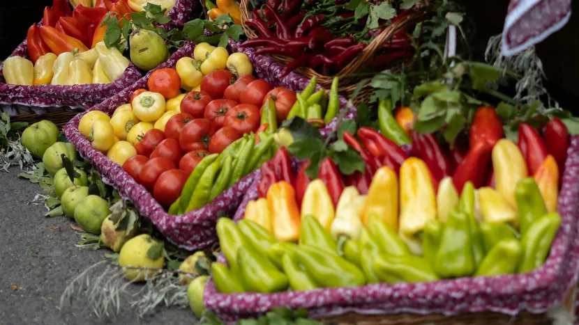 Market baskets overflowing with peppers, tomatoes and chillies.